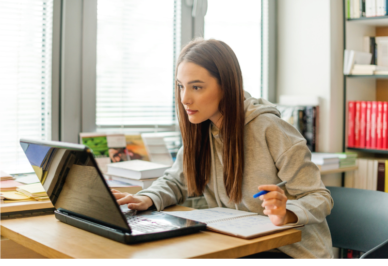 Étudiante travaillant sur ordinateur avec un cahier devant le clavier !